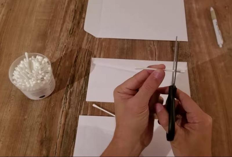 Cotton swab being cut with scissors.